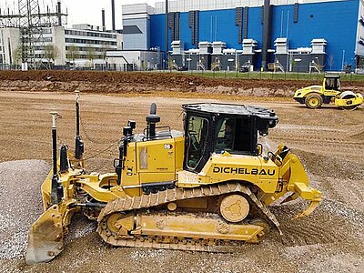 Raupe mit Maschinensteuerung in der Seitenansicht schiebt Kies auf einer Baustelle