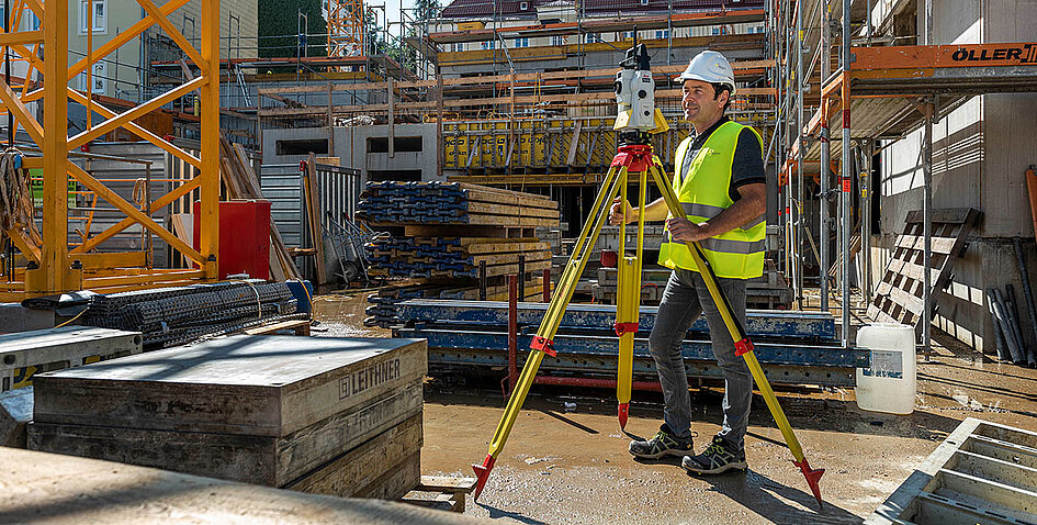 Ein Bild auf einer Baustelle im Bereich Hochbau, ein Mitarbeiter von Smart Systems vermisst mit Leica Produkten die Baustelle.