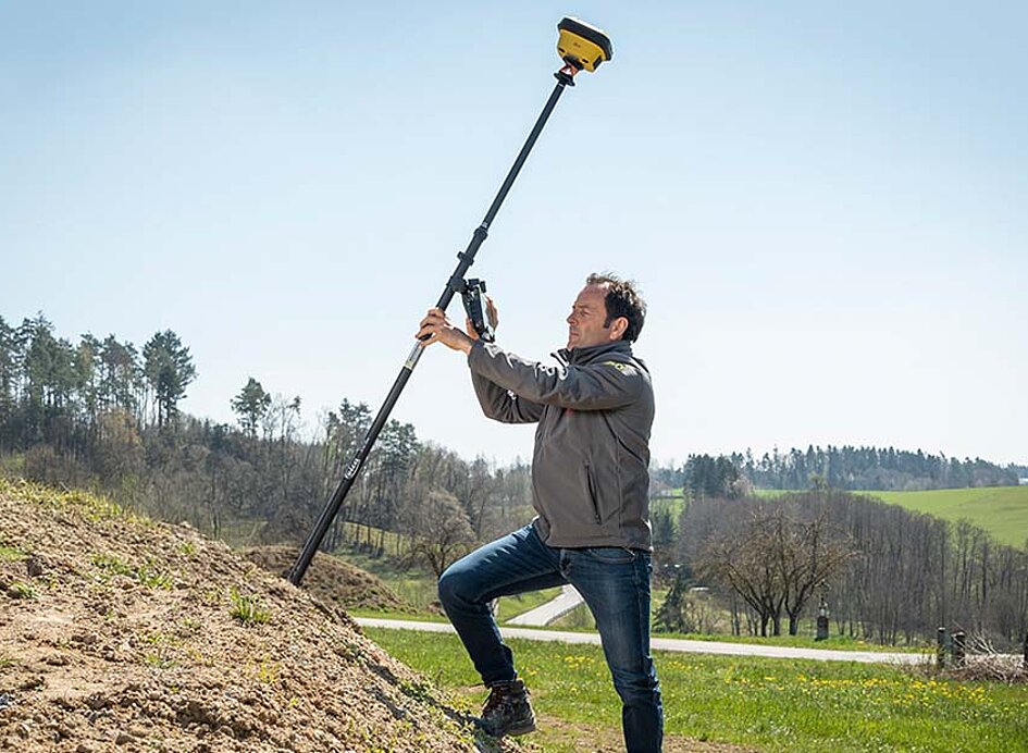 Auf einem Erdhaufen mit GNSS-Rover iCG70 die Umgebung ausmessen