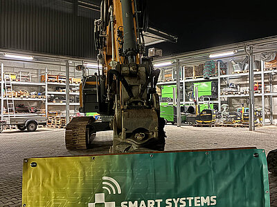 Raupenbagger hält einen Banner von Smart Systems Technology bei Nacht