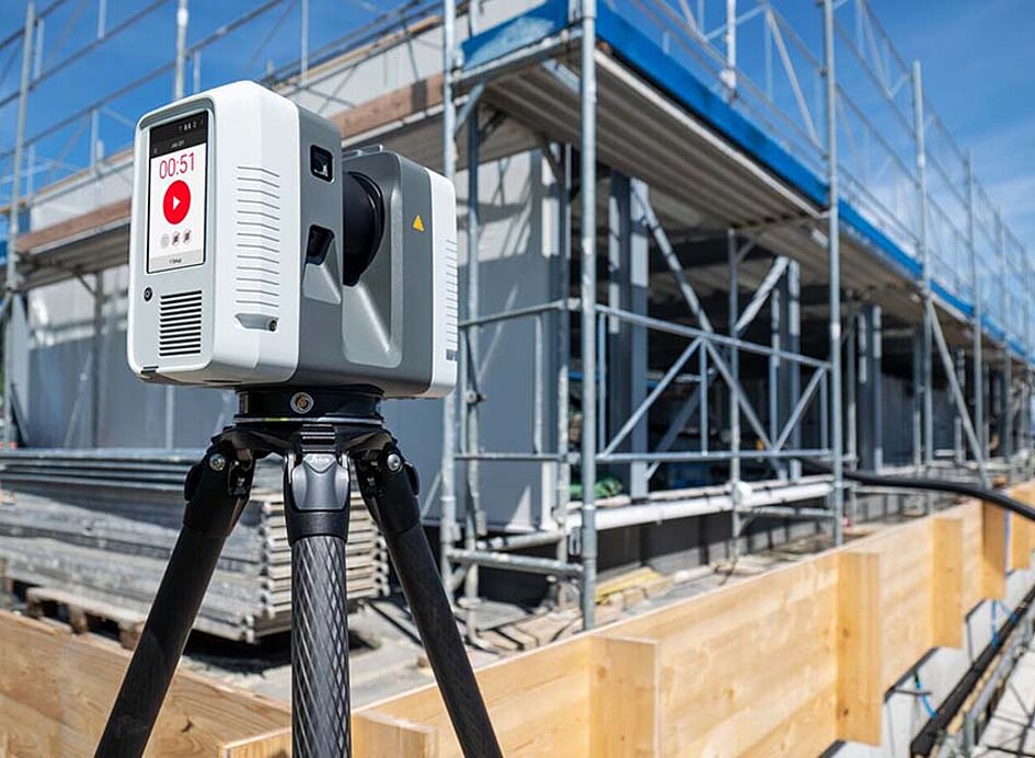 Ein RTC360 von Leica steht vor einem Gebäude im Bau.