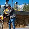 Vermessung einer Baustelle mit einem AP20 Autopole von Leica. Im Hintergrund eine Raupe mit Maschinensteuerung.