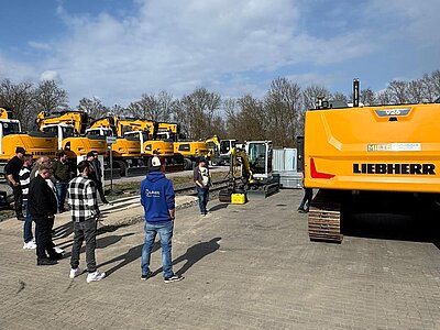 Schulungsteilnehmer erkunden das Gelände inkl Raupenbagger von Liebherr mit Maschinensteuerung von Leica