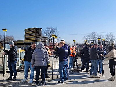 Smart Systems Academy Teilnehmer mit Rover-Stäben vermessen die Umgebung eines Geländes