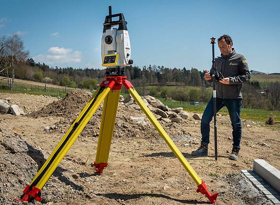 iCR70 Vermessungsgerät gezeigt auf einer Baustelle im Freien mit Vermesser im Hintergrund