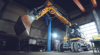 Mobilbagger der in einer Werkstatt steht, ist mit einer Leica 3D-Maschinensteuerung ausgerüstet.