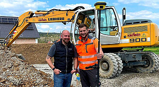 Roverstab und Totalstation im Hintergrund ein Liebherr 900 Mobilbagger