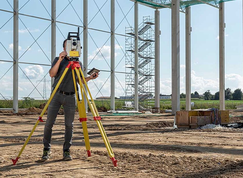 Baustelle für eine Halle auf der ein Vermesser mit einem iCR70 das Gelände vermisst
