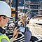 Arbeiterin auf Hochbaubaustelle mit einem BLK3 Vermessungsgerät von Leica in der Hand.