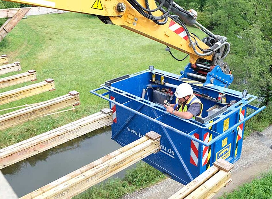 Arbeitskorb mit Arbeiter bei Brückensanierung eingesetzt.