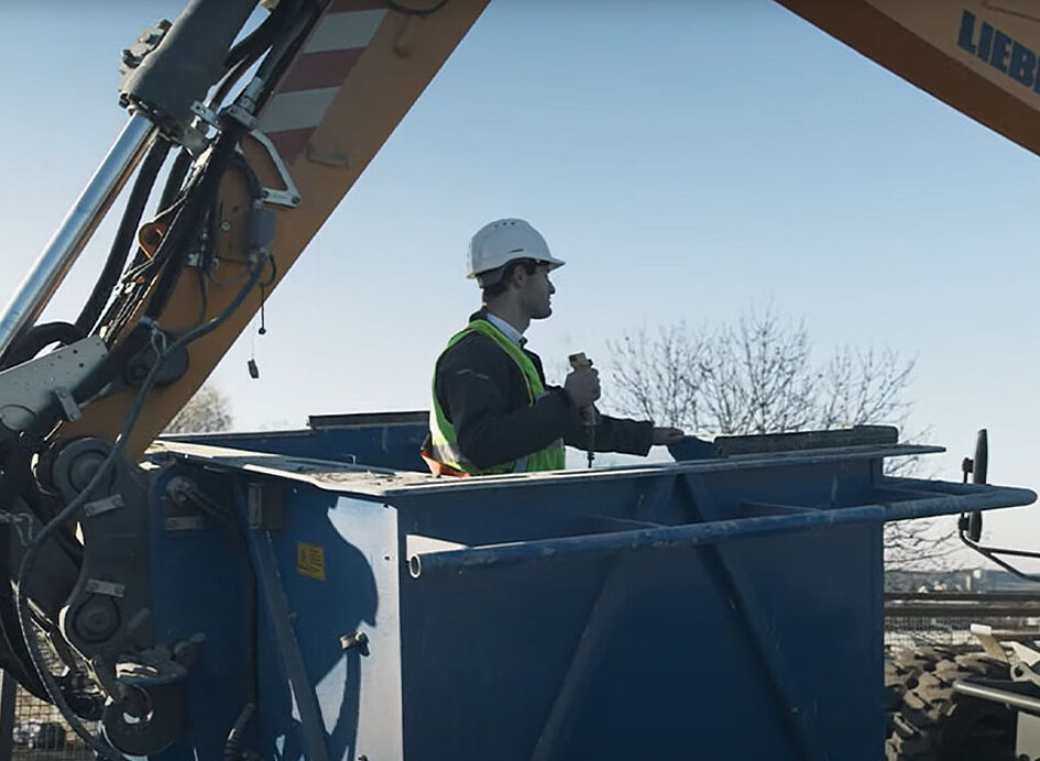 Bagger hält Arbeitskorb mit Arbeiter auf einer Baustelle in Position