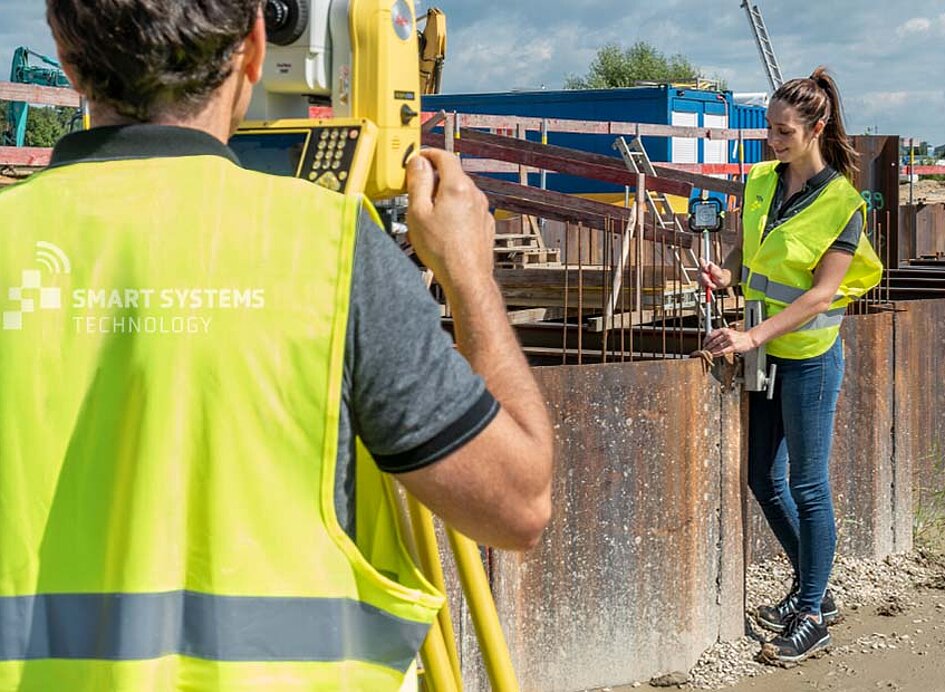 Baustelle Vermessung mit iCB50 zwei Mitarbeiter von Smart Systems stellen Gerät vor