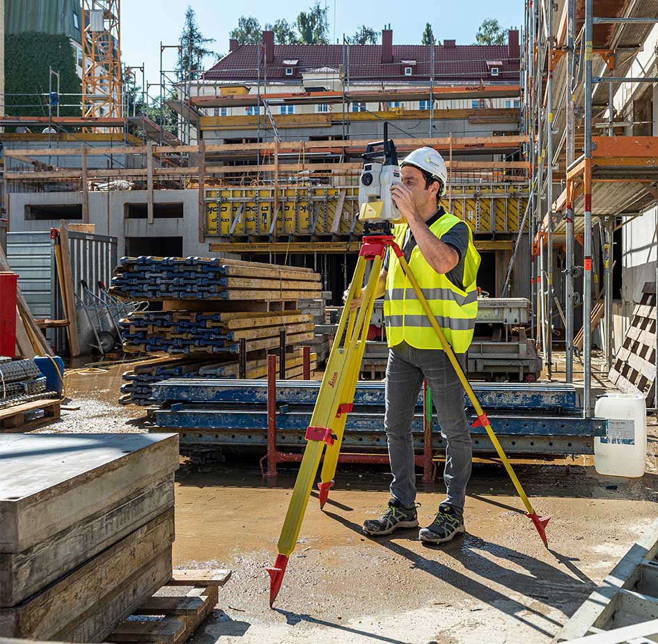 Ein Mitarbeiter von Smart Systems Technology misst mit einer Leica Totalstation auf einer Baustelle die Umgebung aus