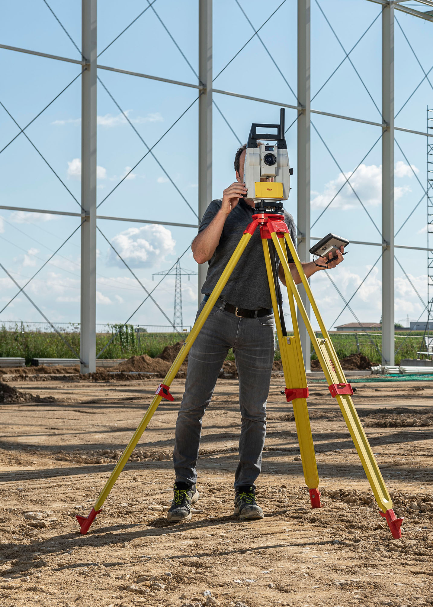 Mann bei der Bedienung eines Tachymeters auf Baustelle