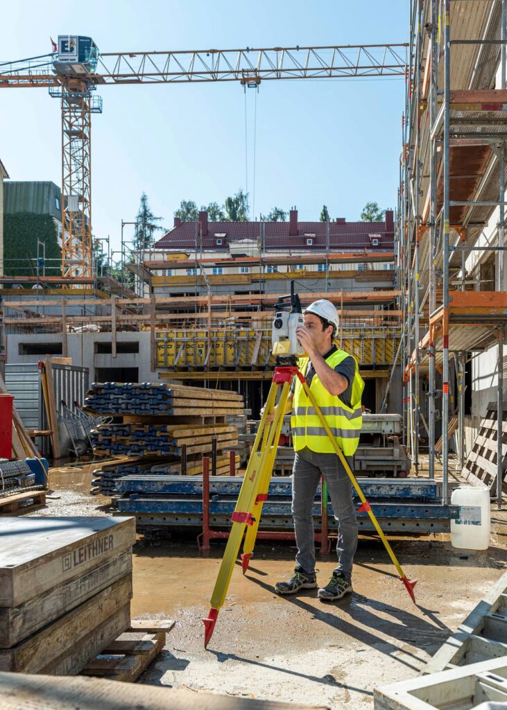 Mann am Tachymeter auf Baustelle